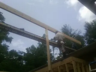 Carpenter setting a ridge beam over a new addition frame — Ice Dam Removal by Roofing Brothers in Converse