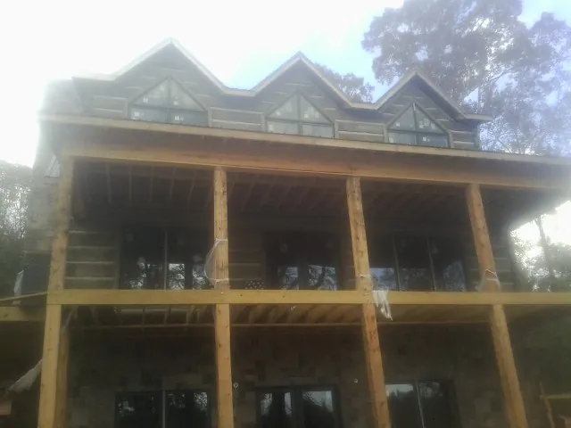 Dormers and porch framing on a large log home under construction — Roof Coating work by our crew in Converse
